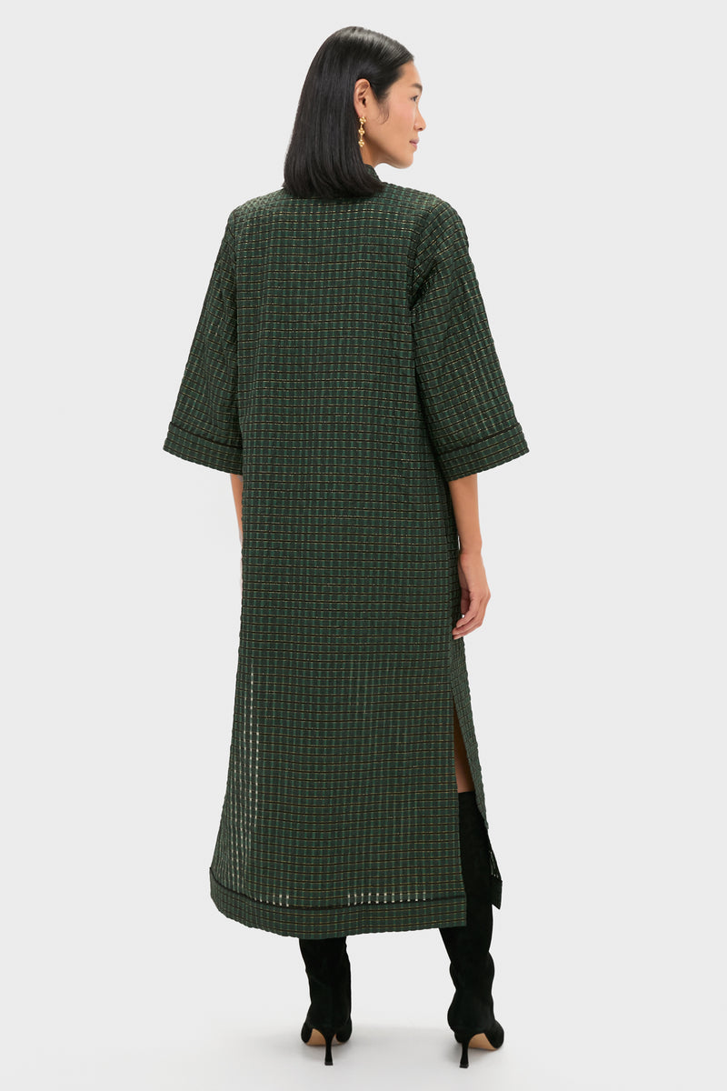 Woman wearing the classic Metallic Green Plaid Indy Maxi Dress with elbow-length sleeves and knee-high boots, exuding effortless style and high-end sophistication.