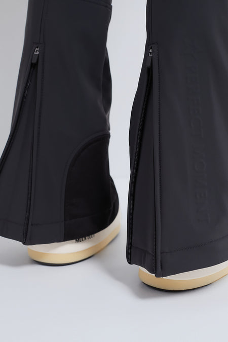 Close-up of classic Black Aurora High Waist Ski Pant with zippers at hems, showcasing effortless style and high-end, fun design with cream-and-beige platform shoes.
