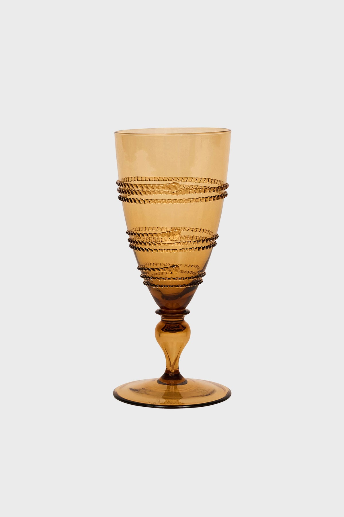 Amber-colored, mouth-blown glass goblet by Juliska featuring a textured spiral design around the bowl, with a short stem and circular base.
