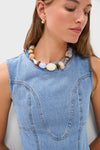 Woman wearing a sleeveless blue denim dress, small gold hoop earrings, and a Lizzie Fortunato mixed-media necklace featuring chunky beads and freshwater pearls.