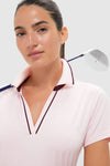 Woman wearing Pink Short Sleeve Performance Jersey Caroline Polo, showcasing a classic, effortless style with a white golf club, ideal for fun, high-end activities.