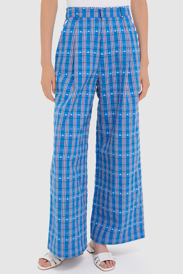 A person wearing CeliaB high-waisted, wide leg blue plaid pants with vertical and horizontal stripes, paired with white sandals.