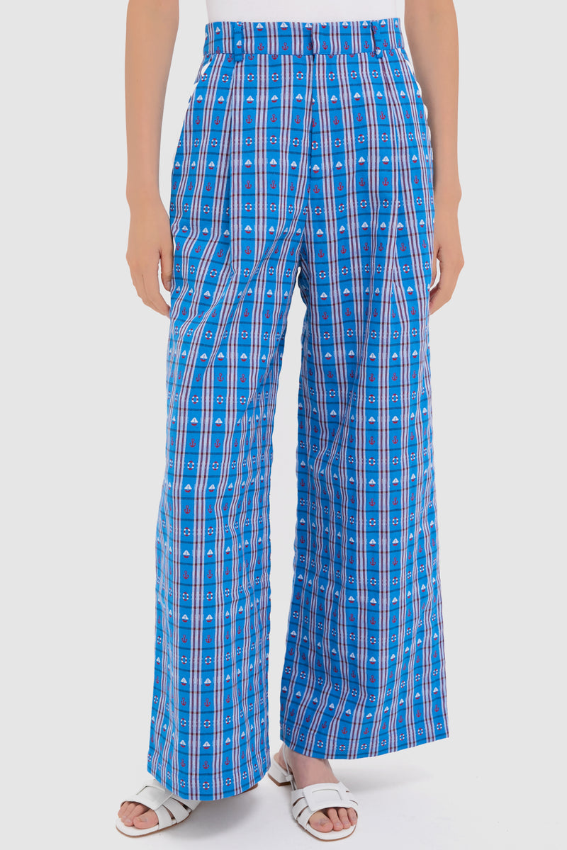 A person wearing CeliaB high-waisted, wide leg blue plaid pants with vertical and horizontal stripes, paired with white sandals.