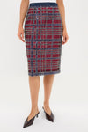 A person wearing a Tuckernuck knee-length pencil skirt in red and navy plaid, perfect for holiday parties, paired with black pointed-toe shoes.