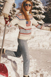 Person in snow, wearing American Flag Christie Turtleneck Sweater with a fair isle pattern, stylishly shoveling snow, embodying classic, effortless winter fashion.