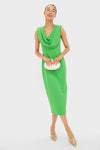 Woman in a classic, bright green Yuri Gown, featuring an effortless draped cowl neckline, holding a white clutch, paired with fun, high-end gold heeled mules.