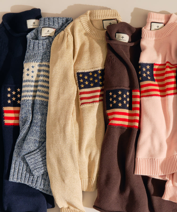 Americana sweaters with the American flag in the middle. Featuring navy, blue, beige, brown, and pink sweaters. 