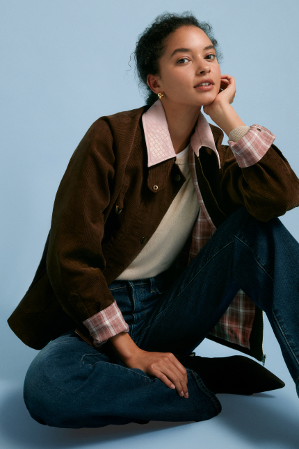 Woman in a brown jacket with a pink collar. 