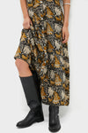Person wearing the Story Print Santiago 3 Maxi Dress with a classic animal and foliage print, revealing leg and paired with effortless, high-end leather boots for a fun, stylish look.