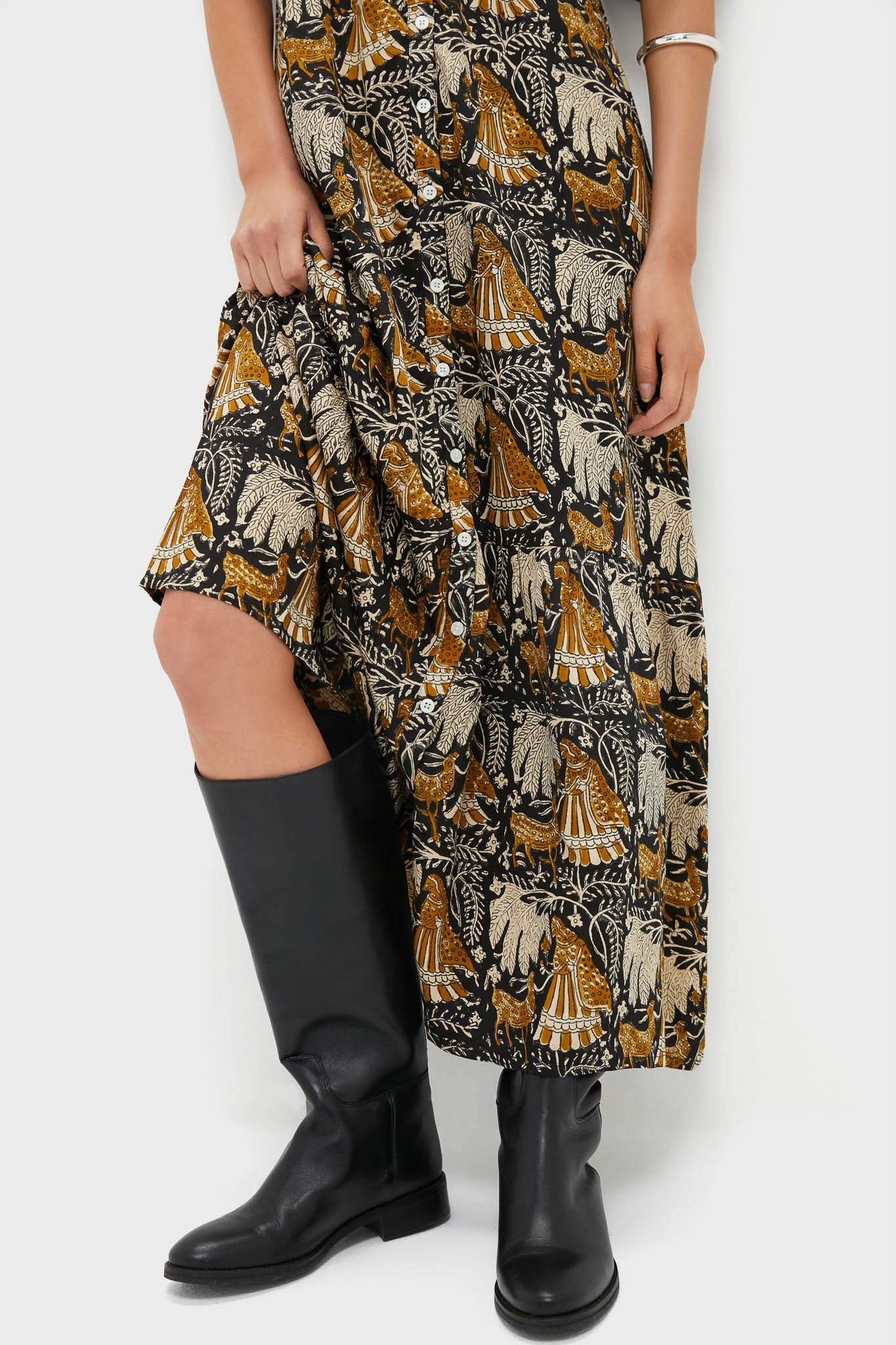 Person wearing the Story Print Santiago 3 Maxi Dress with a classic animal and foliage print, revealing leg and paired with effortless, high-end leather boots for a fun, stylish look.
