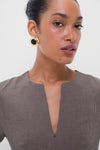 Woman wearing Onyx Alva Earrings, a classic, high-end accessory with an oversized gold design and black center, paired with a micro-houndstooth top. Effortlessly fun and stylish.