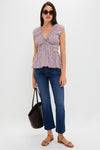 Woman in a classic, effortless Burgundy Maia Stripe Hedda Top, featuring a V-neckline and peplum hem, paired with jeans and sandals for a fun, high-end look.