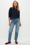 Woman models the Navy Long Sleeve Pique Holmes Boyfriend Polo with a classic, effortless style, showcasing its boxy silhouette and textured fabric, paired with light jeans and red flats.