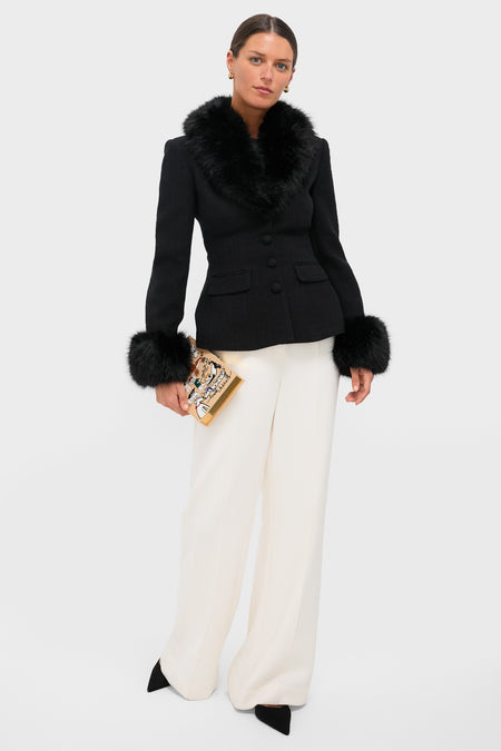 Woman in tailored jacket and wide-leg trousers holds the Latte Les Chiens Caramel Book Clutch, a classic, high-end accessory blending effortless style and fun whimsy.