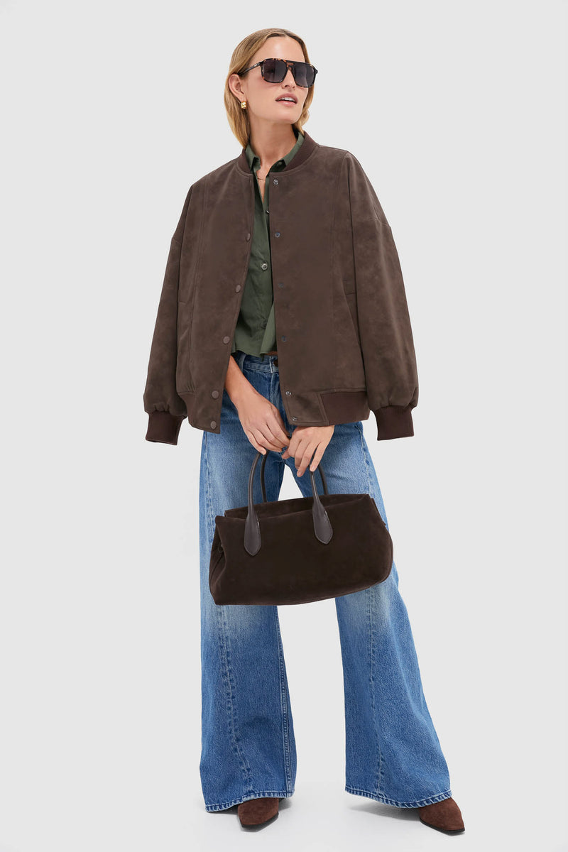 Woman modeling the classic Chocolate Alfie Jacket, an effortless, high-end faux leather bomber paired with wide-leg jeans, pointed suede shoes, and a matching tote.