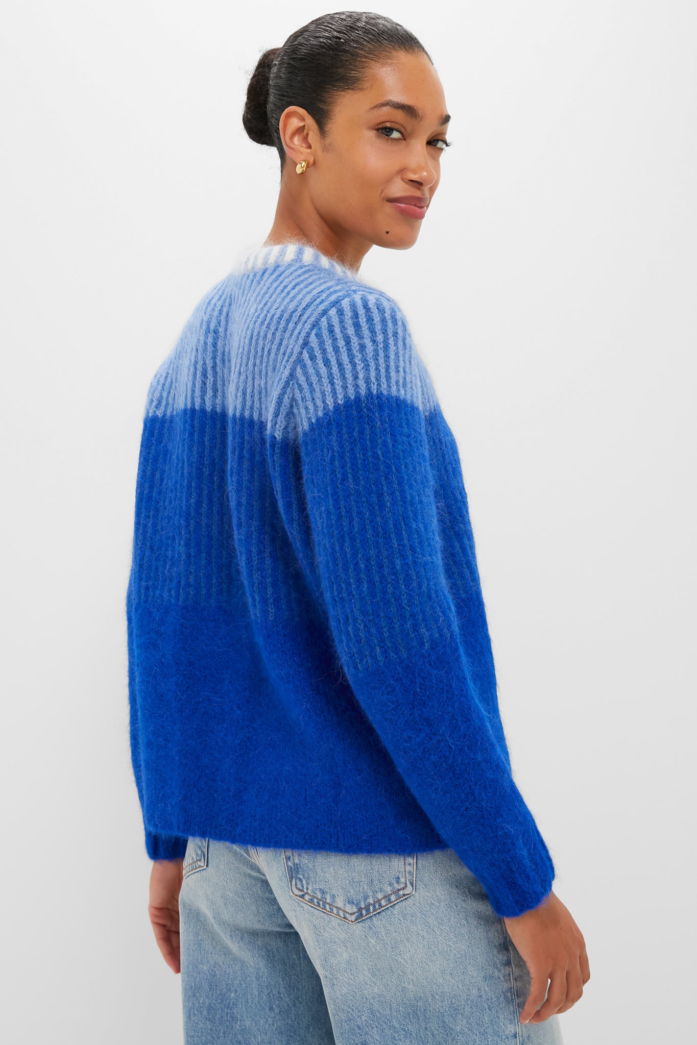 Woman wearing the classic Blue Cocha Sweater, effortlessly combining sky blue and cobalt tones, paired with light-wash jeans for a fun, high-end look.