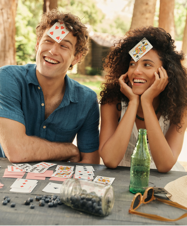 Man and woman playing cards with cards on their head