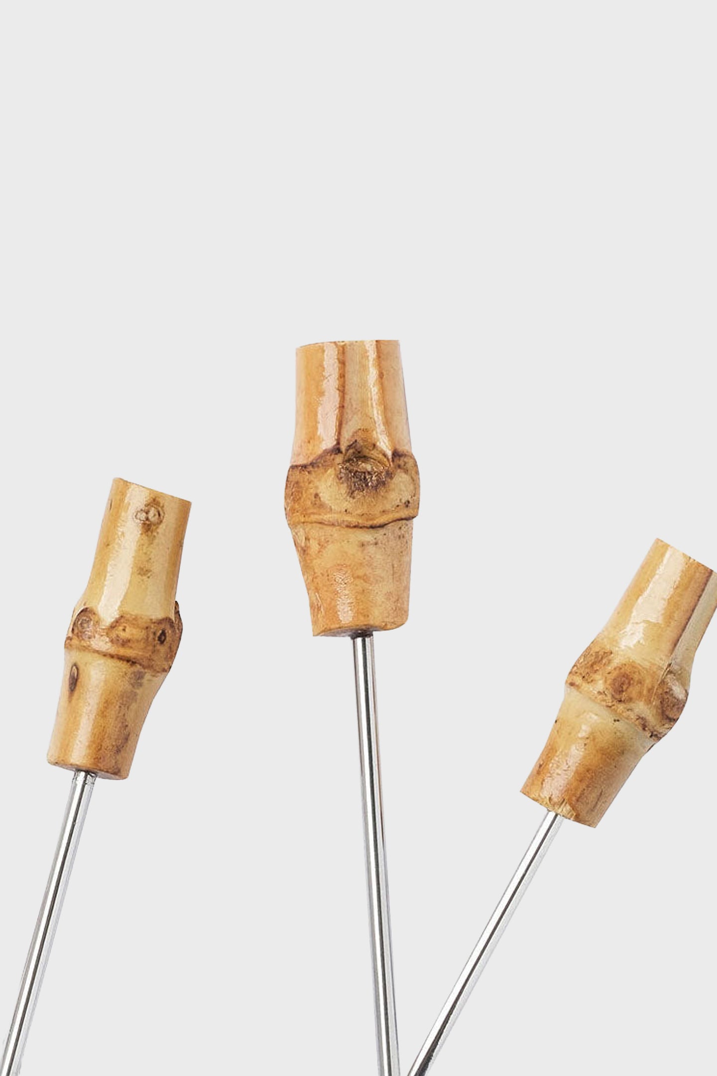 Three Joanna Buchanan metal skewers with bamboo handles are displayed against a plain white background.