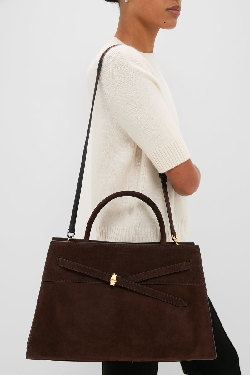 Side view of a person with the classic Espresso Large Suede Veronica Beard Dash Bag, featuring an effortless trapezoidal design, fun suede belt detail, and high-end Italian craftsmanship.