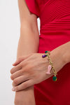Close-up of a woman's forearm in a red dress, wearing the Multi Tesori Fish Bead Bracelet. This chunky, fun charm bracelet features classic, brightly colored enamel charms for an effortless, high-end look.