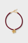 Maroon Lelani Necklace: A classic, effortless design featuring a burgundy braided cord, gold-tone fittings, and a removable gold-plated flower charm for versatile, high-end style.