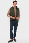 Model in classic olive Winter Finn Gilet, effortlessly styled with a light blue shirt, camel sweater, navy chinos, and brown loafers, showcasing high-end, fun fashion.