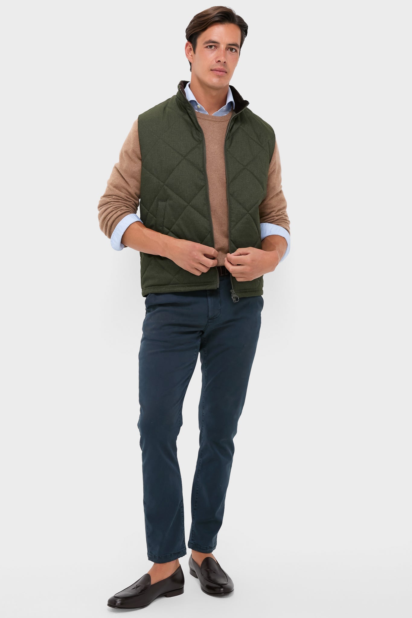 Model in classic olive Winter Finn Gilet, effortlessly styled with a light blue shirt, camel sweater, navy chinos, and brown loafers, showcasing high-end, fun fashion.