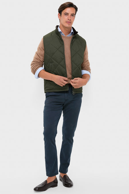 Model in classic olive Winter Finn Gilet, effortlessly styled with a light blue shirt, camel sweater, navy chinos, and brown loafers, showcasing high-end, fun fashion.
