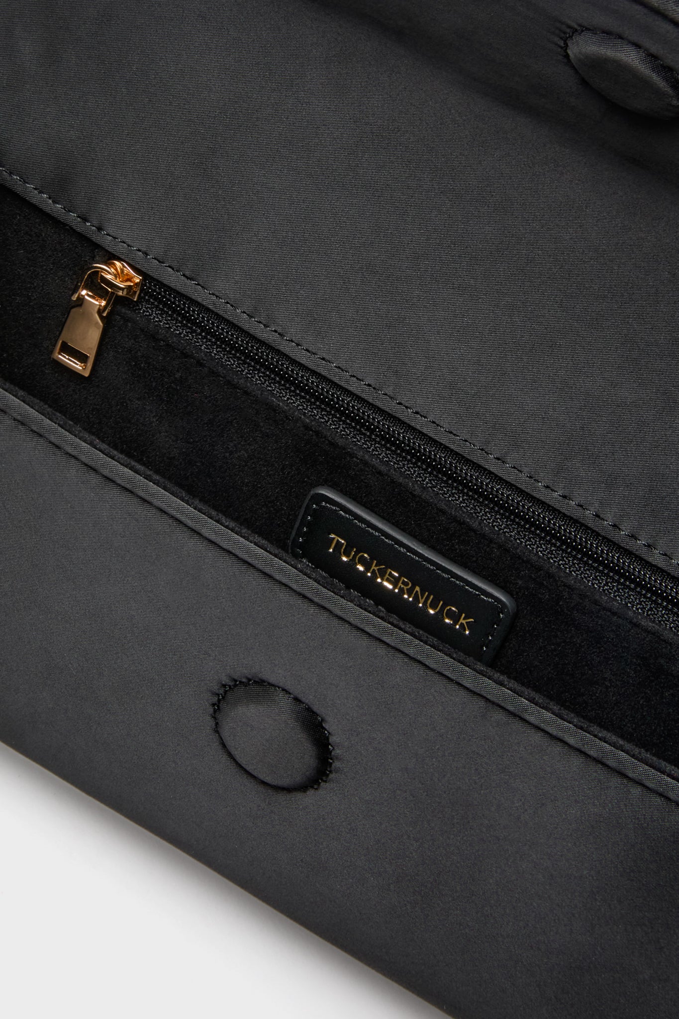 Close-up of Black Satin Gabrielle Clutch interior, showcasing a classic zippered pocket with gold hardware and a small suede-lined pocket, embodying effortless high-end style.