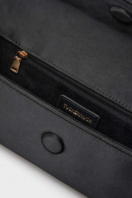 Close-up of Black Satin Gabrielle Clutch interior, showcasing a classic zippered pocket with gold hardware and a small suede-lined pocket, embodying effortless high-end style.