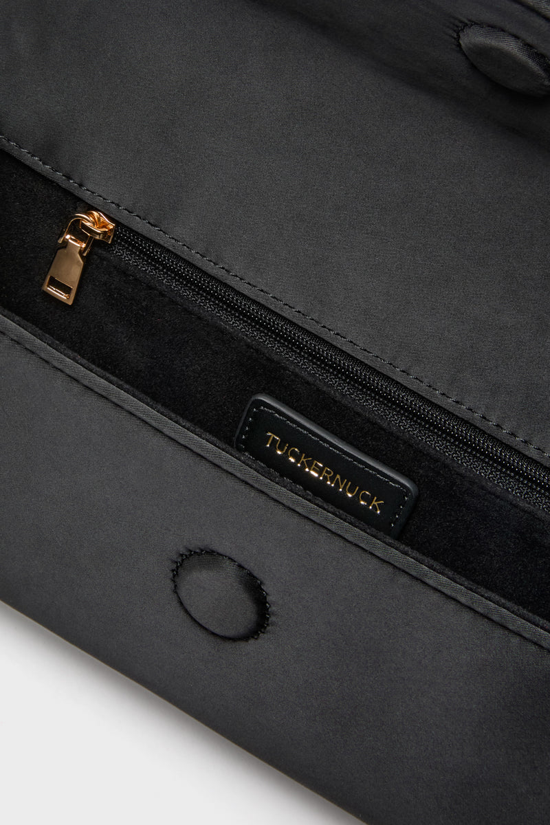 Close-up of Black Satin Gabrielle Clutch interior, showcasing a classic zippered pocket with gold hardware and a small suede-lined pocket, embodying effortless high-end style.
