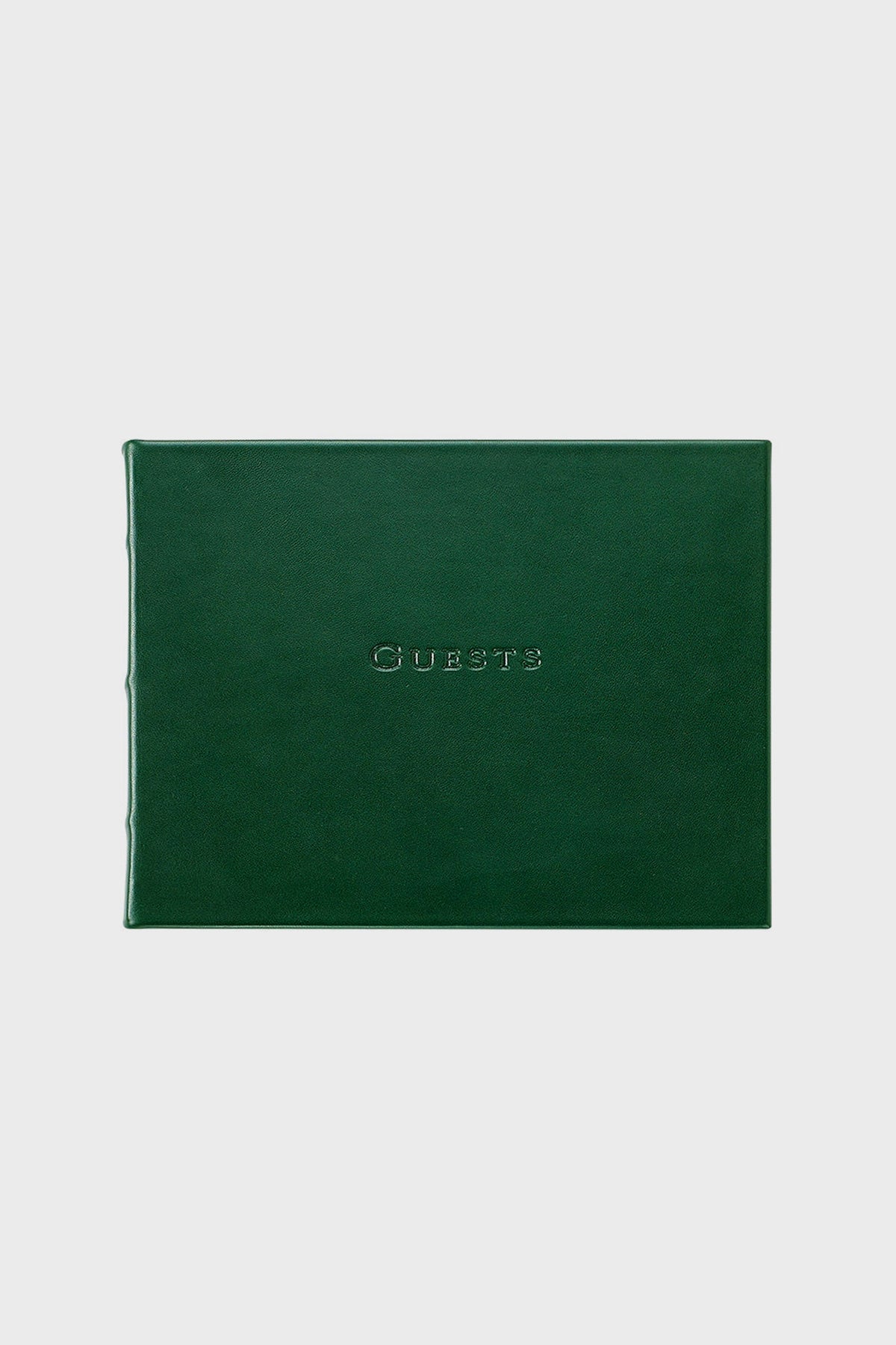 A closed, dark green leather guest book by Graphic Image with "Guests" embossed in uppercase on the front cover.