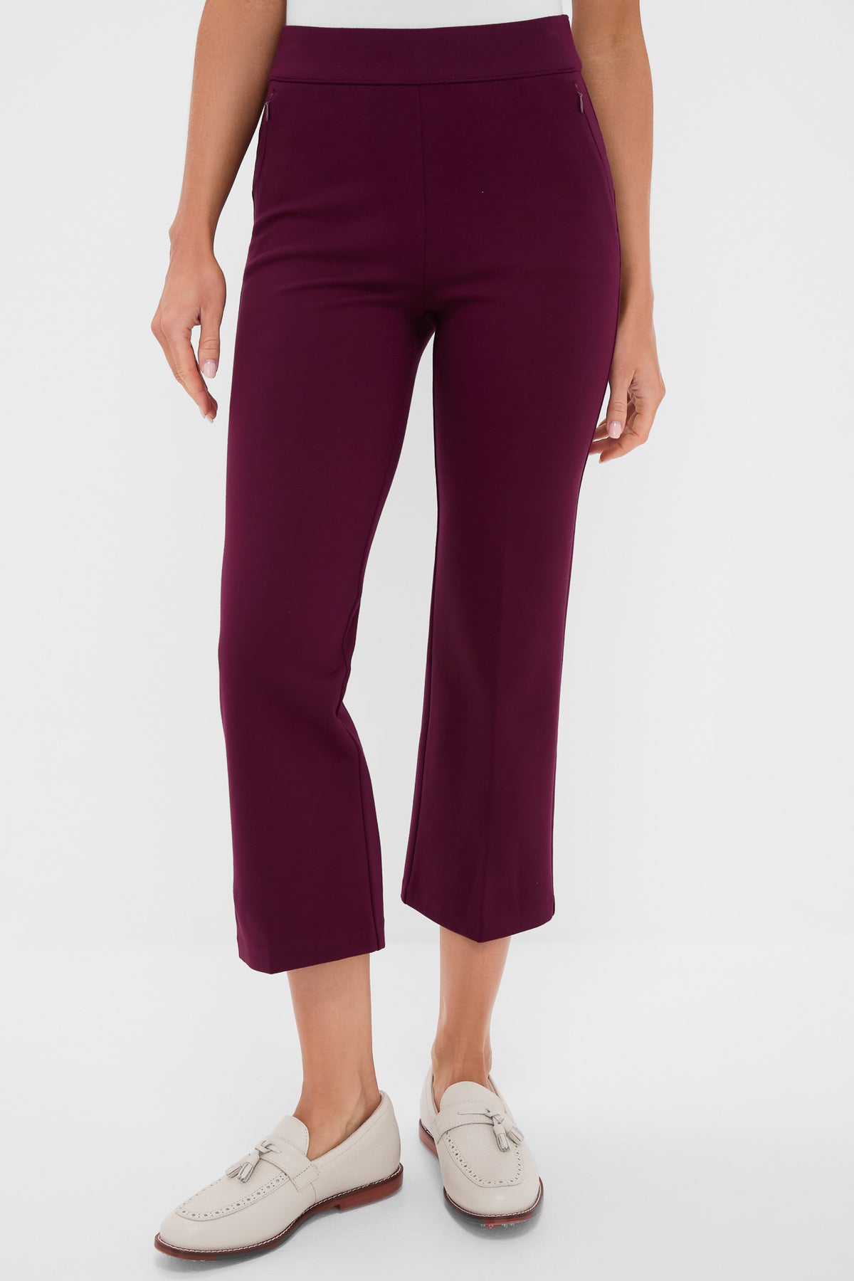 A person wears Tnuck Sport elevated cropped pants in purple with a white top and light-colored loafers, creating a modern, polished look.