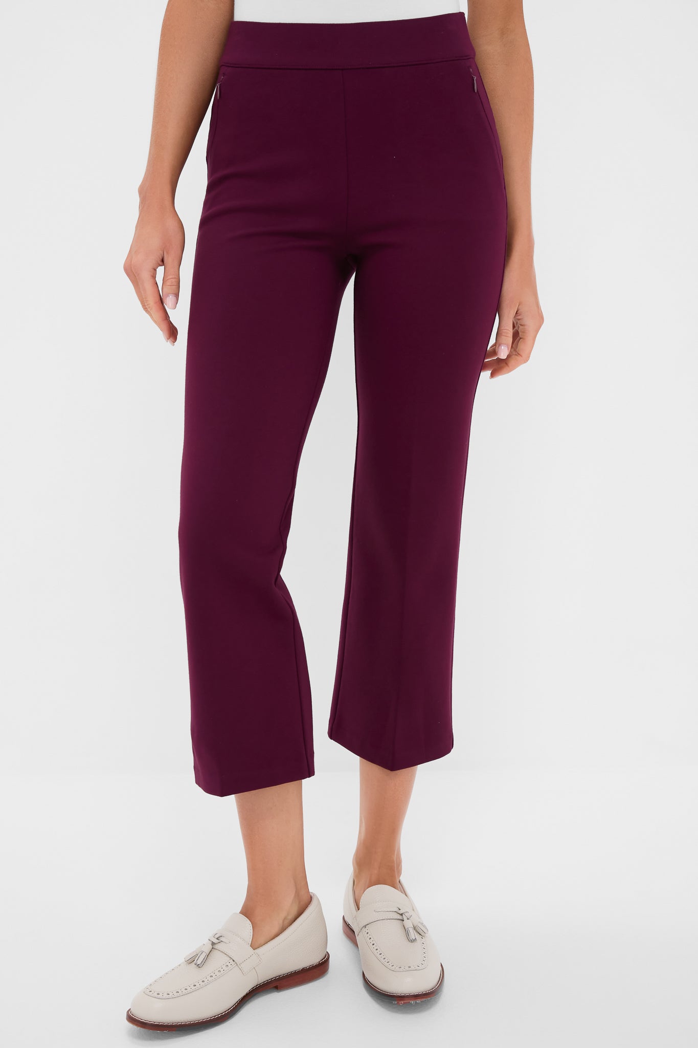 A person wears Tnuck Sport elevated cropped pants in purple with a white top and light-colored loafers, creating a modern, polished look.
