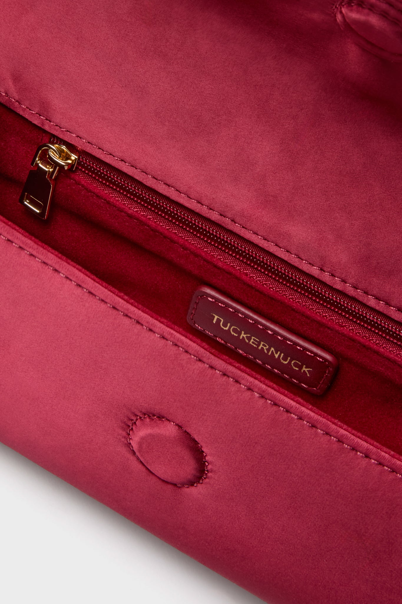 Cranberry Satin Gabrielle Clutch interior with classic gold zip pocket, leather Tuckernuck label, and effortless magnetic snap closure, combining high-end flair and fun functionality.