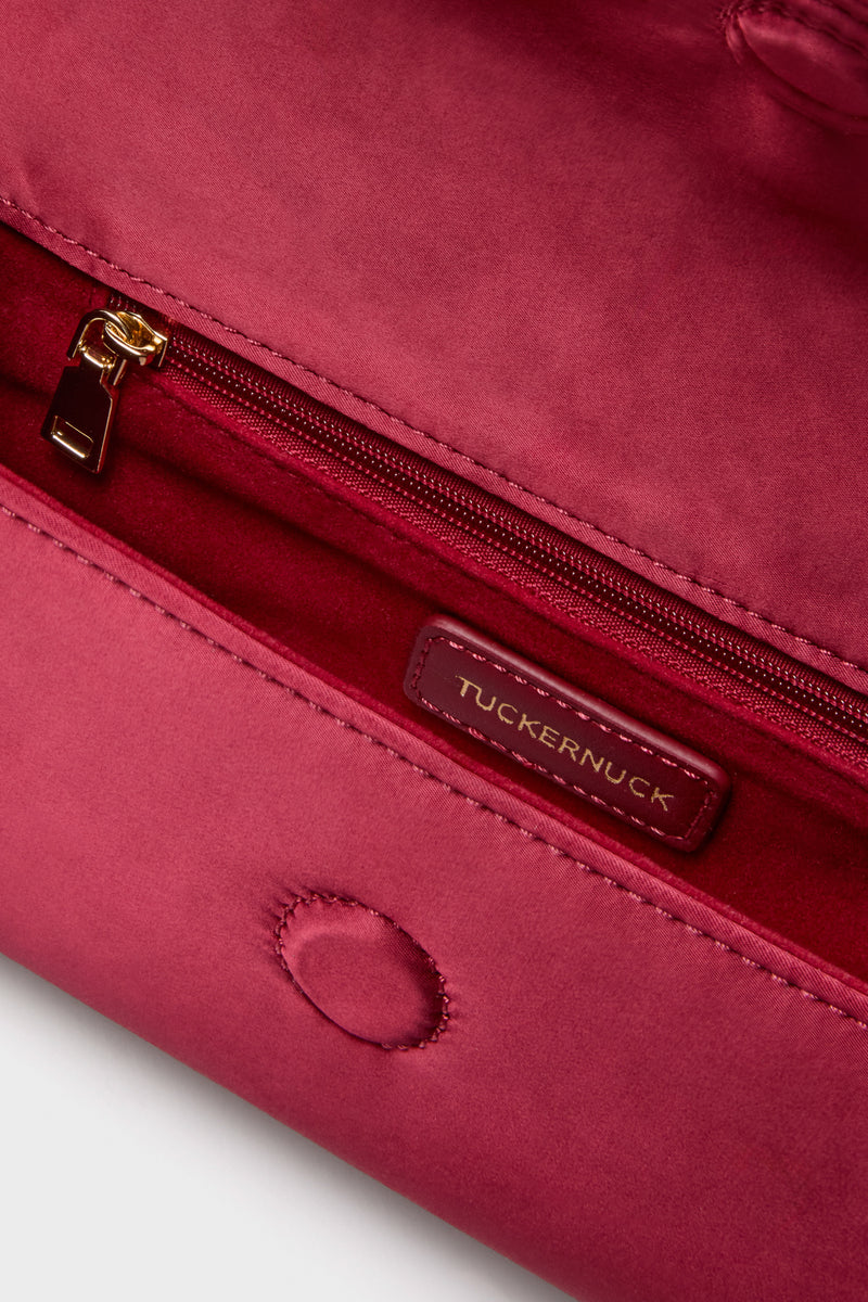 Cranberry Satin Gabrielle Clutch interior with classic gold zip pocket, leather Tuckernuck label, and effortless magnetic snap closure, combining high-end flair and fun functionality.