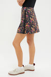 Baroque Floral 16 Inch Performance Stretch Woven Karrie Golf Skirt modeled with classic elegance, featuring a playful floral print, side-seam detail, and paired with chic loafers.