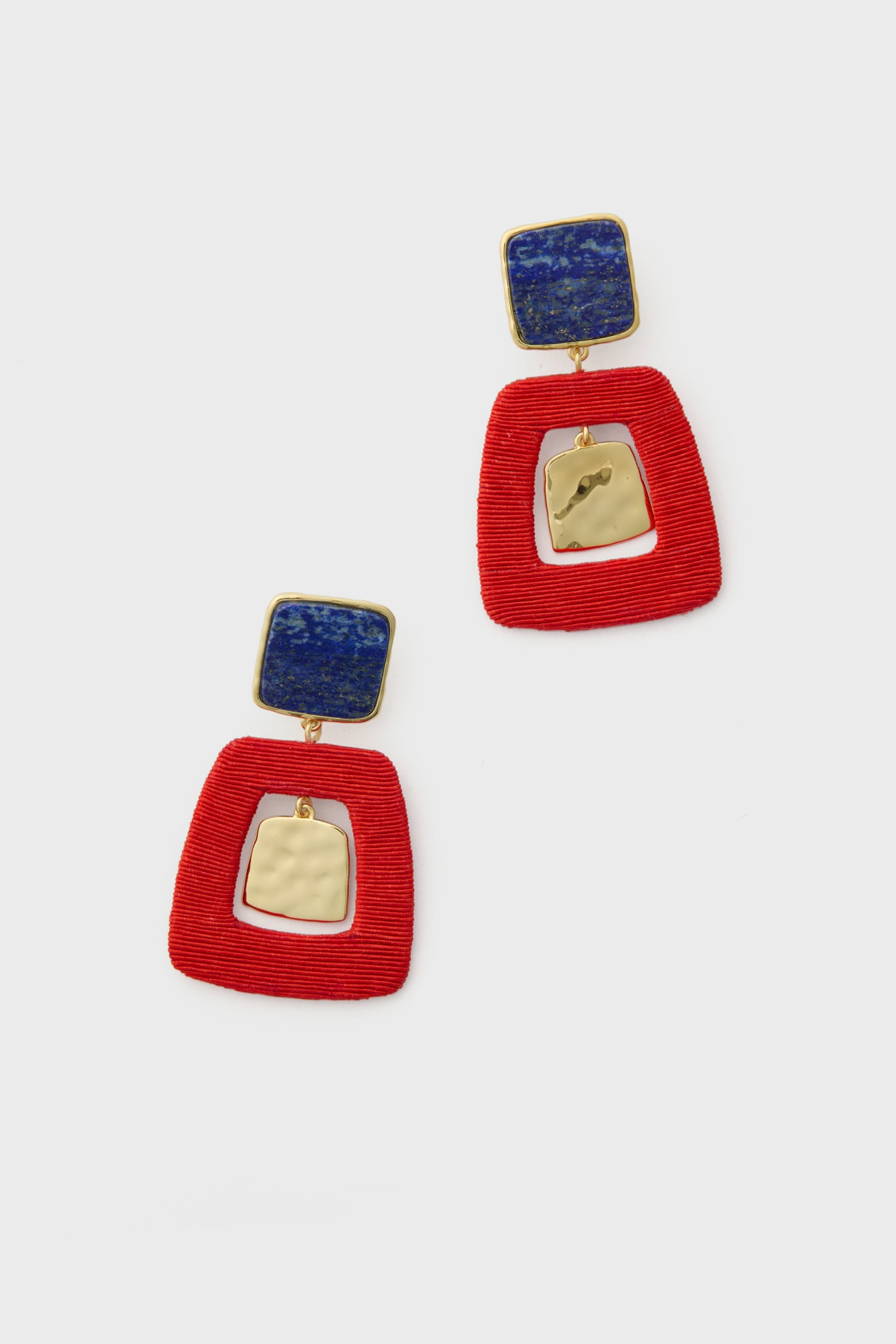 A pair of woven earrings, with a blue square top, textured gold-plated brass center, and bold red geometric open-frame bottom.