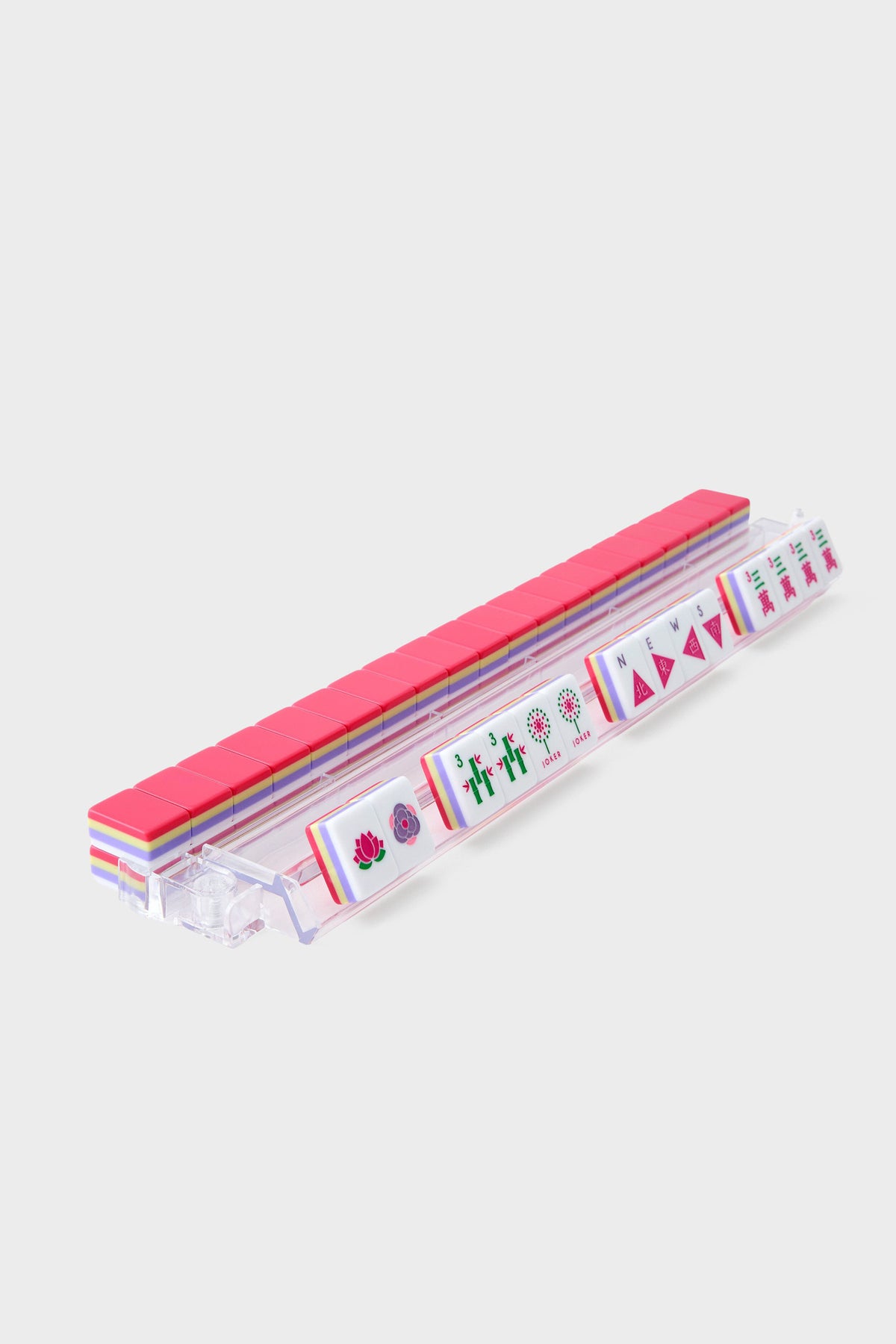 An Oh My Mahjong clear plastic rack holds a row of upright, hand-painted mahjong tiles, each face displaying unique symbols and patterns.