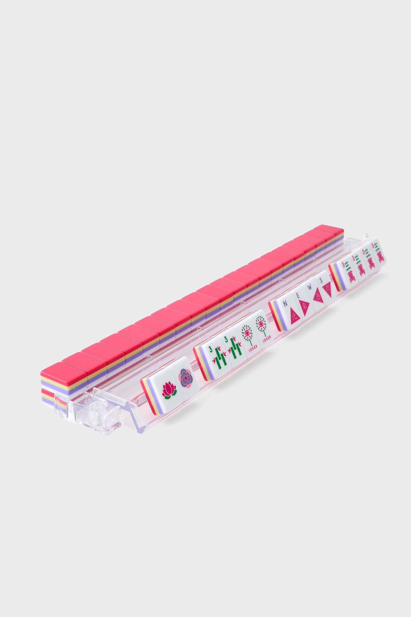 An Oh My Mahjong clear plastic rack holds a row of upright, hand-painted mahjong tiles, each face displaying unique symbols and patterns.