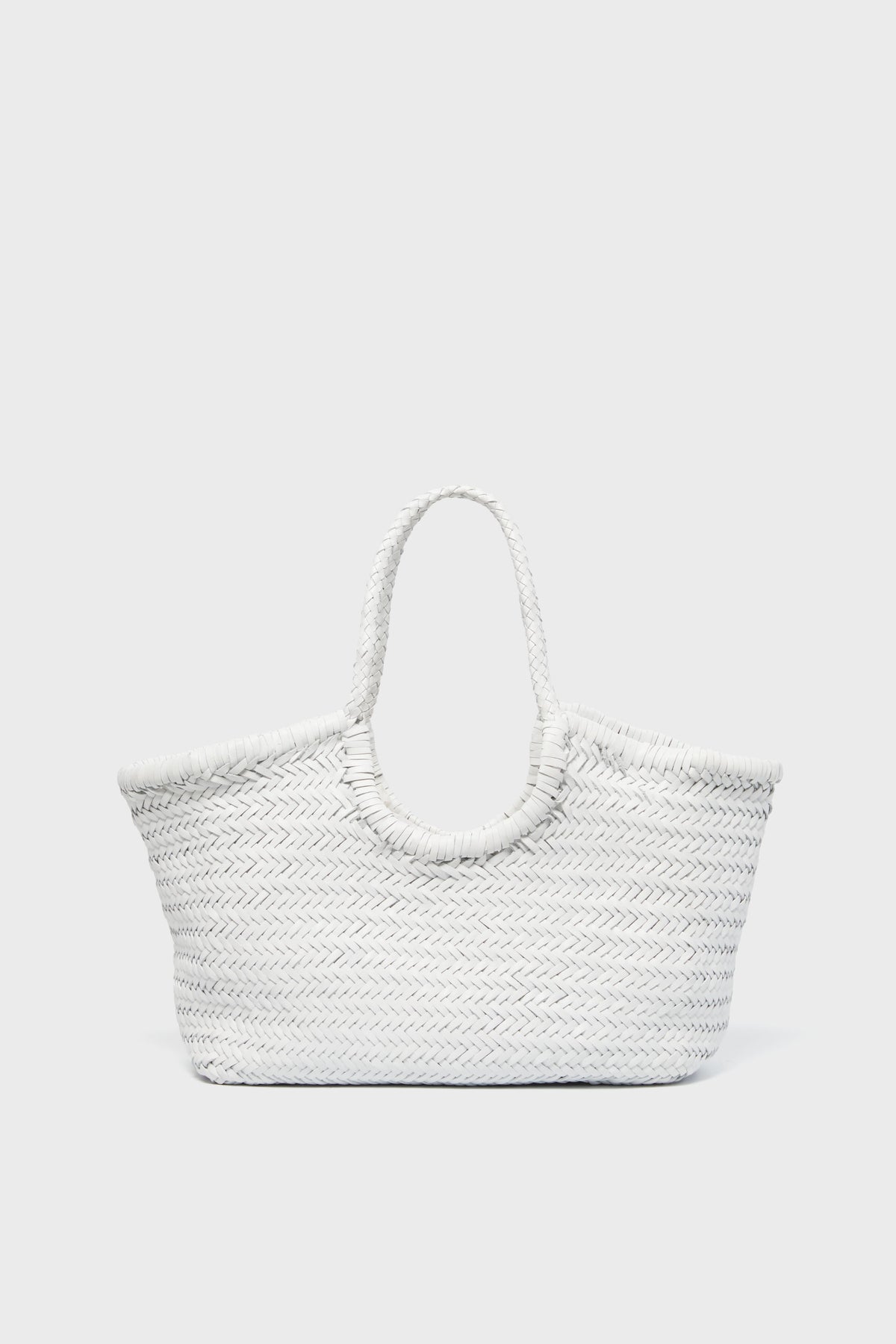 A white handwoven tote bag by Dragon Diffusion, featuring two handles, is displayed in a minimalist light gray setting.