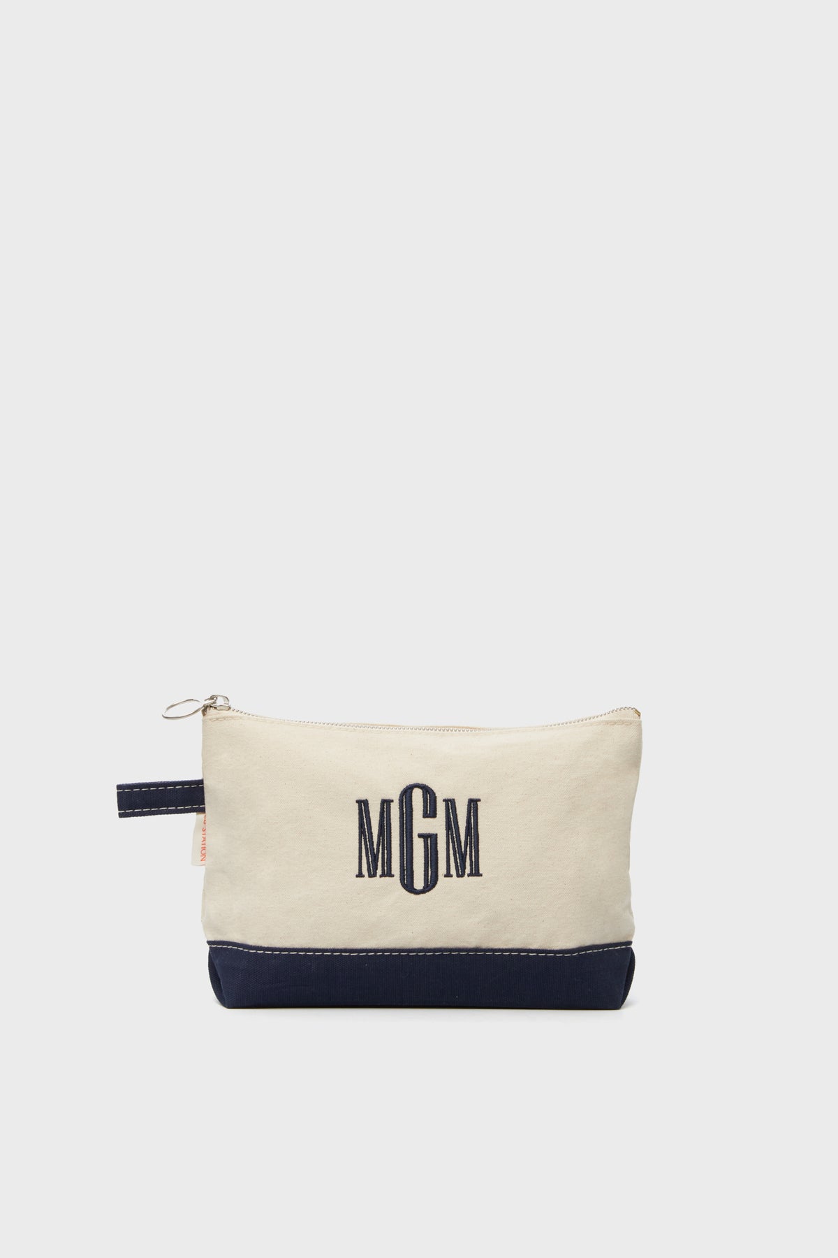 The CB Station beige cotton canvas zippered pouch features a navy base and MGM monogram embroidered in navy thread, making this makeup bag a stylish travel essential.