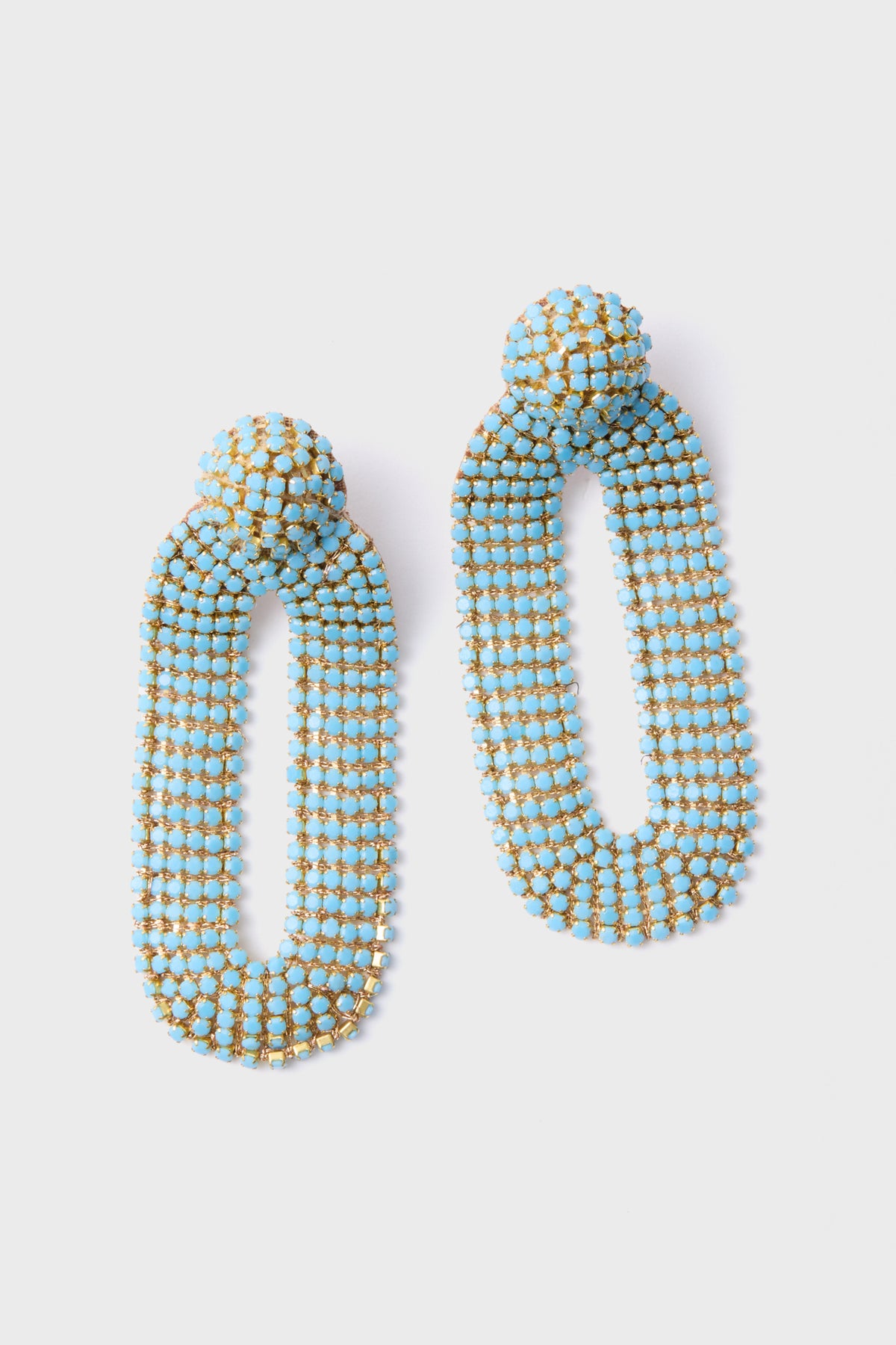 The Deepa Gurnani Turquoise Bianca Earrings are handcrafted dangle earrings with elongated ovals, adorned with blue and gold beads and inspired by Indian hand embroidery.