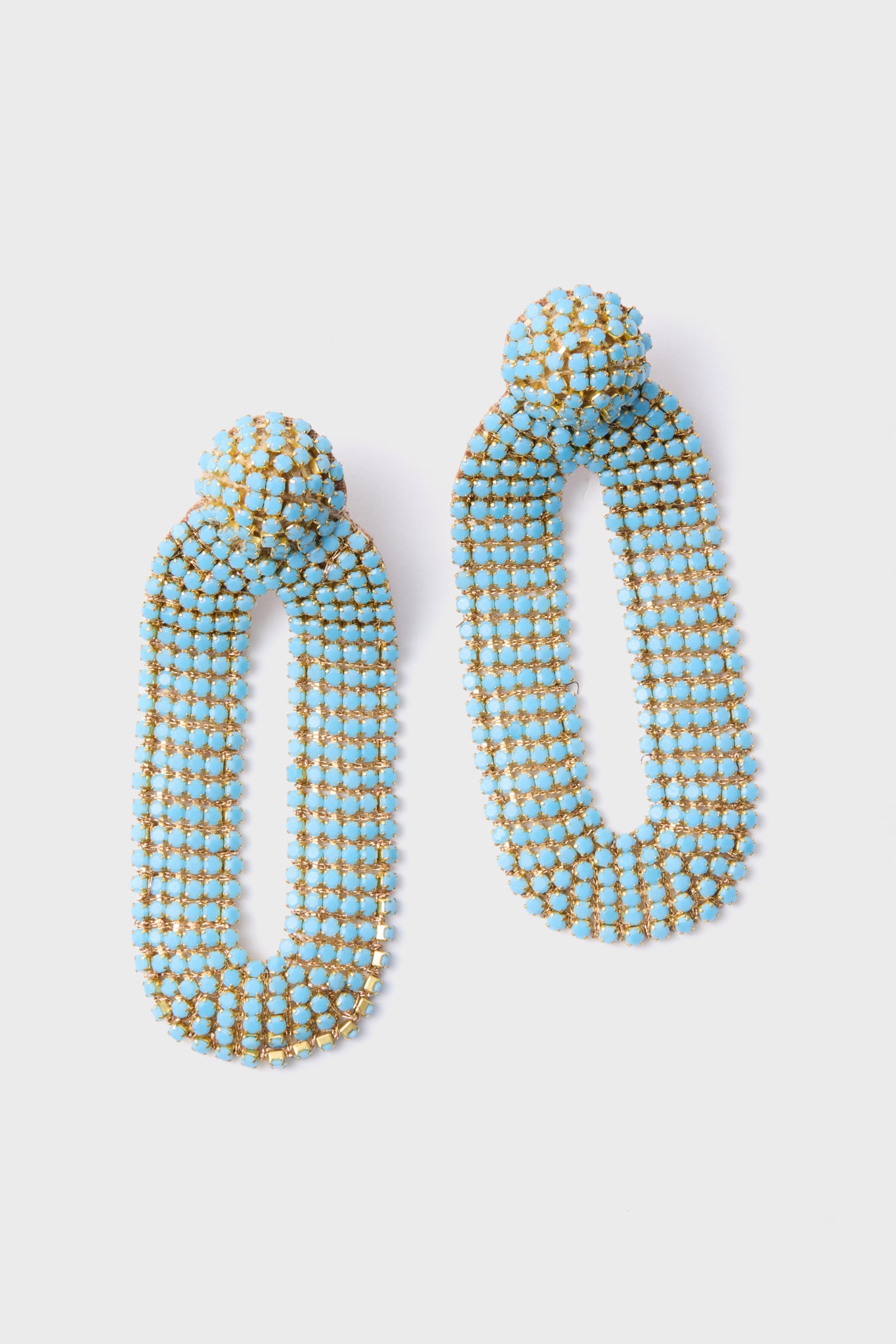 The Deepa Gurnani Turquoise Bianca Earrings are handcrafted dangle earrings with elongated ovals, adorned with blue and gold beads and inspired by Indian hand embroidery.