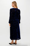 Woman in a classic Navy Burnout Velvet Odette Maxi Dress with floral pattern, long blouson sleeves, and fitted waist, styled with black mules.