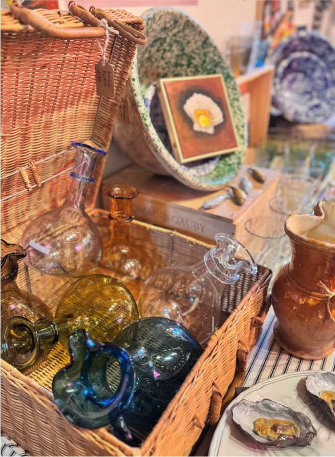 A display of glass vases in a large woven trunk. 