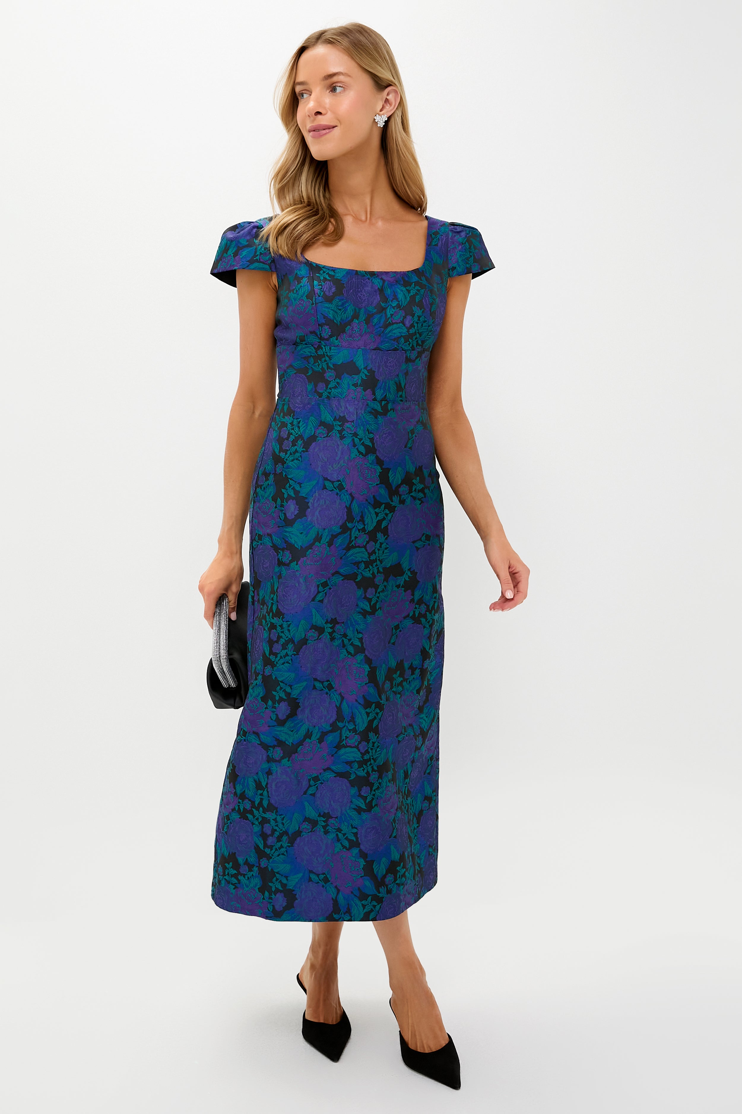 Woman wearing a classic Navy & Indigo Jacquard Archibald Maxi Dress with a column silhouette, holding a black clutch, styled with slingback heels for an effortless, high-end look.