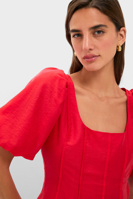 Woman wearing classic Ruby Taffeta Annalise Blouse with short puff sleeves and square neckline, paired with gold hoop earrings, exuding an effortless, high-end style.
