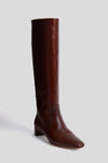 A single Loeffler Randall tall Espresso Indy boot in rich brown vachetta leather, featuring a low square heel and slightly pointed toe, displayed against a plain light grey background.