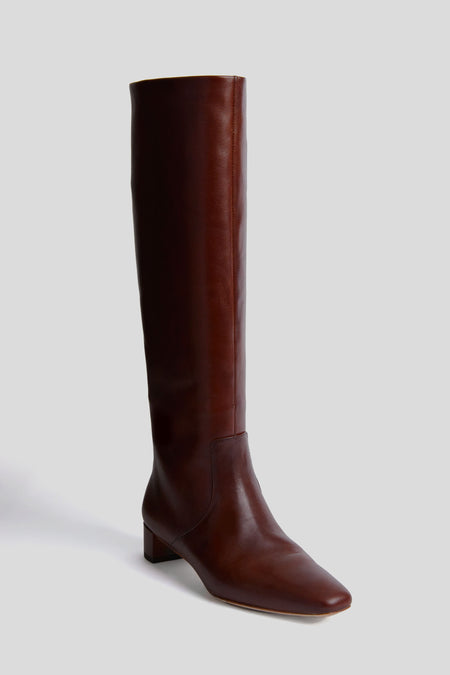 A single Loeffler Randall tall Espresso Indy boot in rich brown vachetta leather, featuring a low square heel and slightly pointed toe, displayed against a plain light grey background.